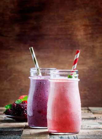 Smoothies from blackberries and strawberries in glass bottle, vintage wooden background, selective focusの写真素材