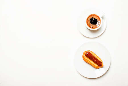 Eclairs cake and espresso coffee with foam, white background, top view