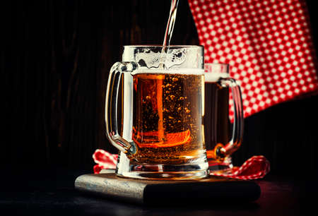 Two glasses of german light beer, beer poured into mug, dark bar counter, selective focusの写真素材