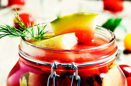 Marinated or pickled watermelon in a glass jar, vintage wooden background, selective focus