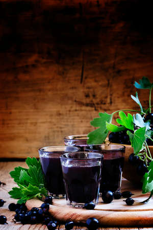 Homemade liqueur made from black currants and fresh berries, vintage wooden background, selective focusの写真素材