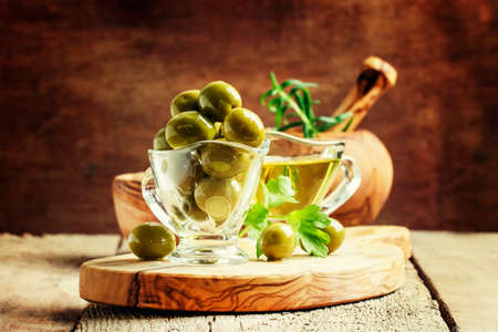 Spanish green olives in glass bowl and olive oil, rustic style, selective focusの写真素材
