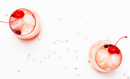 Festive pink cocktail for Valentine's day, couple of glasses, white background with hearts, top viewの写真素材
