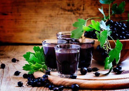 Homemade liqueur made from black currants and fresh berries, vintage wooden background, selective...