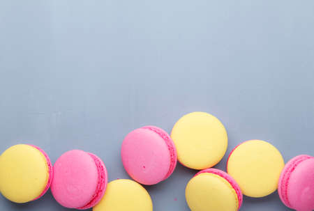 Pink yellow macaroons cake on gay background, neon color, place for text, creative layout, top viewの写真素材