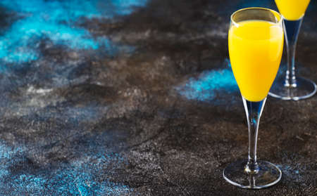 Mimosa alcohol cocktail with orange juice and dry champagne or sparkling wine in glasses, blue background, copy spaceの写真素材