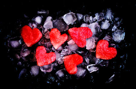 Red sweet watermelon hearts on crushed ice, dark food background, top viewの写真素材
