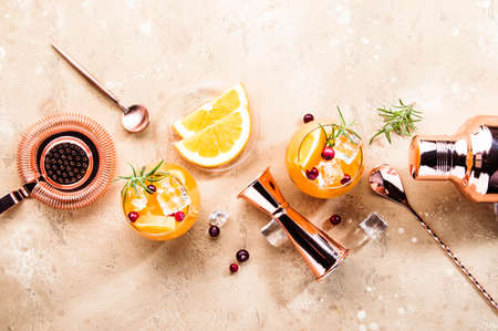 Orange Cranberry Rosemary and Vodka cocktail, copper bar tools, beige background, hard light, top viewの写真素材