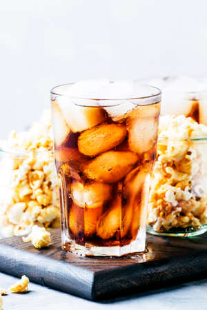 Cola with ice and sweet popcorn, ready for cinema, gray background, selective focus