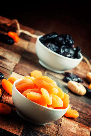 Dried apricots in bowl, vintage wooden background, selective focus