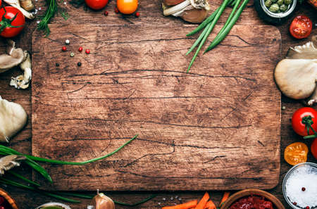 Food cooking background, ingredients for preparation vegan dishes, vegetables, roots, spices, mushrooms and herbs. Old cutting board. Healthy food concept. Rustic wooden table background, top viewの写真素材