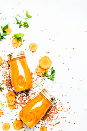 Carrot smoothies with flax seeds in glass bottles, vegan beverage, healthy drink for clean raw diet, white background, top viewの写真素材