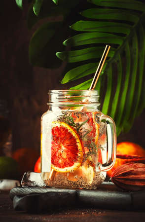 Summer cold detox drink with red orange, citrus fruit juice and chia seeds. Healthy fitness drink. Ingredients for cooking on wooden kitchen table background, selective focusの写真素材