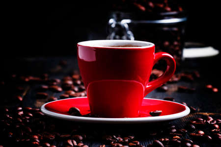 Black coffee in a red cup, black background, selective focus