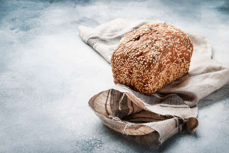 Whole wheat organic rye dark bread with pumpkin seeds, dried fruit, raisins and sesame seeds on gray...
