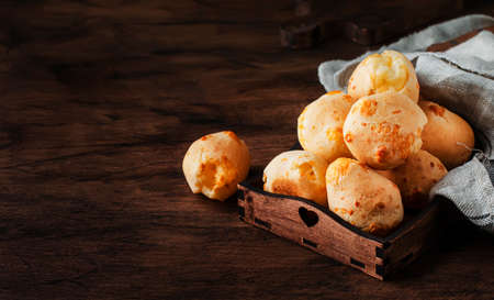 Cheese buns in wooden bowl, rustic kitchen table background, copy space, selective focusの写真素材
