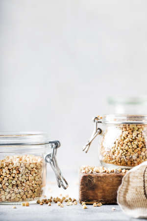 Green buckwheat in glass jar, healthy vegan food or raw diet concept, gray kitchen table background, selective focusの写真素材