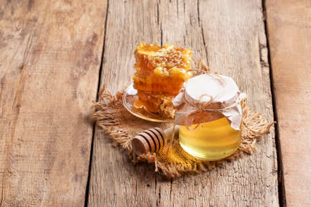 Honey jar and honeycomb, vintage wooden kitchen table background, copy space, selective focus