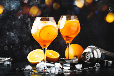 cocktail in big wine glass with orange and ice, summer alcoholic cold drink, dark bar counter with steel bar tools, copy spaceの写真素材