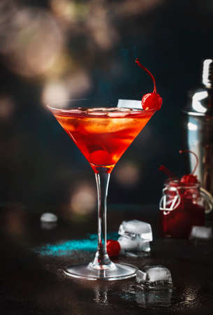Manhattan alcoholic cocktail with bourbon, red vemuth, bitter, ice and cocktail cherry in glass, night mood image, copy spaceの写真素材