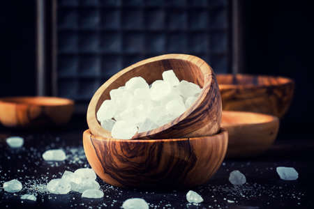 White crystal candy sugar in wooden bowl on black table, selective focusの写真素材