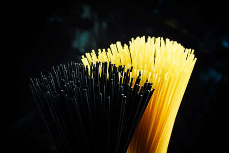 Uncooked spaghetti with tomatoes, black background, selective focusの写真素材