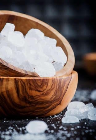 White crystal candy sugar in wooden bowl on black table, selective focusの写真素材