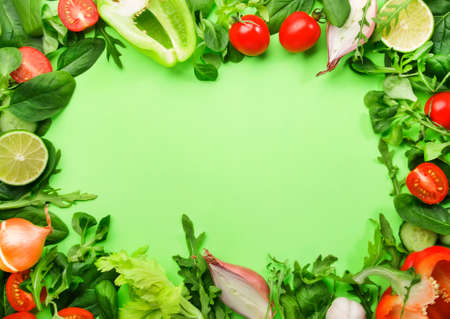 Healthy food background with various green herbs and vegetables. Ingredients for cooking salad. Vegetarian and vegan food concept. Top view, green frame with copy spaceの写真素材