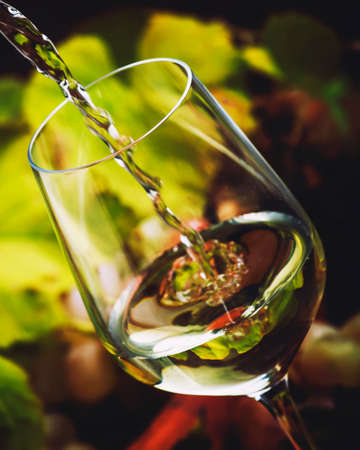 White wine being poured into a glass, vintage wood background, selective focus and long exposureの写真素材