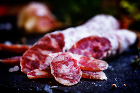 Uncooked jerked sausages from pork and bacon, rosemary, olives and peppers, black background, selective focusの写真素材