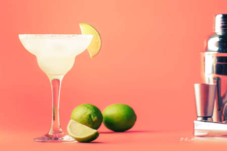 Lime margarita alcoholic cocktail with silver tequila, liqueur, lime juice, sugar syrup, salt and ice, festive trendy pink background, copy spaceの写真素材