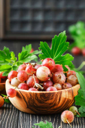 Sweet gooseberries summer harvest in bowl, wooden kitchen table backgroundの写真素材
