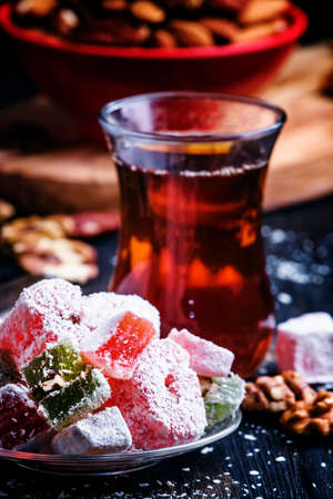 Black tea and candy with nuts on a dark background, selective focusの写真素材