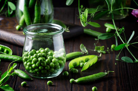Green peas in glass jar, brown background, selective focusの写真素材