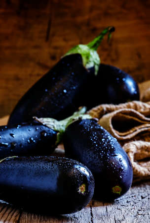 Purple eggplants in a canvas bag in a vintage wooden background in rustic style, selective focusの写真素材