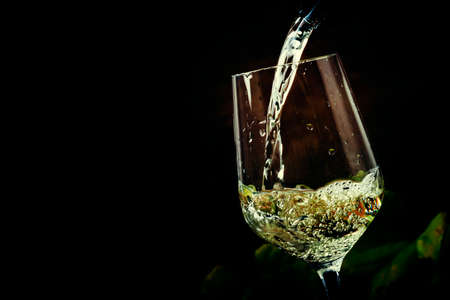 White wine being poured into a glass, vintage wood background, selective focus
