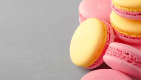 Pink yellow macaroons cakes on gray blue table background, place for text, trendy minimalism style,...