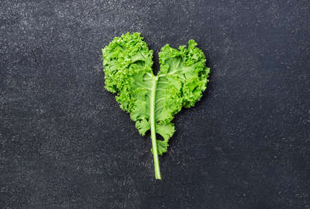 Kale cabbage. Green vegetable leaves, top view on black background, healthy eating, vegetarian foodの写真素材