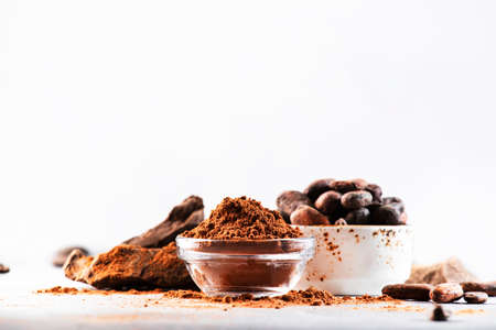 Organic cocoa powder, cocoa beans, grated cocoa lump on gray background. Copy space
