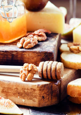Parmesan cheese, figs, nuts, honey and baguette - snack to white and red wine, vintage wooden background, toned image, selective focusの写真素材