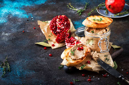 Delicious chicken liver pate on toasted bread with pomegranate seeds and thyme, dark kitchen background table, place for text, selective focusの写真素材