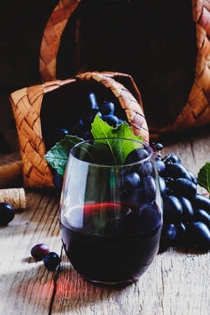 Red wine and black grapes, dark wood background, selective focusの写真素材