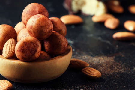 Marzipan, round almond candies in wooden bowl on dark table, selective focusの写真素材