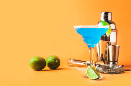 Blue margarita alcoholic cocktail with tequila, liqueur, lime juice, salt and ice, summer yellow background, copy spaceの写真素材