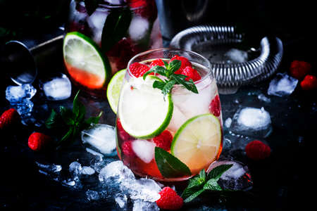 Summer cool alcoholic cocktail raspberry mojito cocktail with lime, rum, mint and ice. Bar tools, gray background, selective focusの写真素材