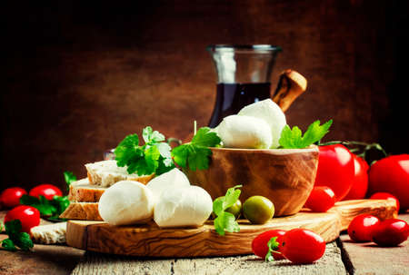 Mozzarella cheese, bread, olives and tomatoes, snack plate. Vintage wooden background, selective focus