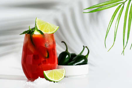 Spicy alcoholic cocktail with vodka, tomato juice, jalapeno pepper, lime and salt, white background,...