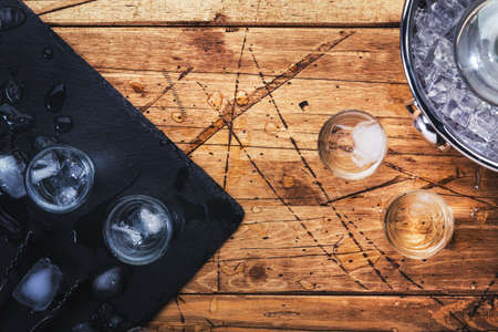 Vodka in shot glasses on wooden background, iced strong drink in misted glass. Top viewの写真素材