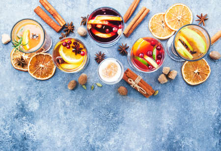 Various autumn or winter seasonal alcohol hot cocktails - mulled wine, glogg, grog, eggnog, warm ginger ale, hot buttered rum, punch, mulled apple cider on gray background, top view with copy spaceの写真素材