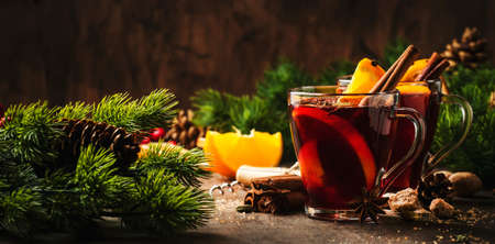 Xmas hot mulled red wine with spices and orange on wooden rustic table. Traditional Christmas or New Year warming drink in festive table settingの写真素材